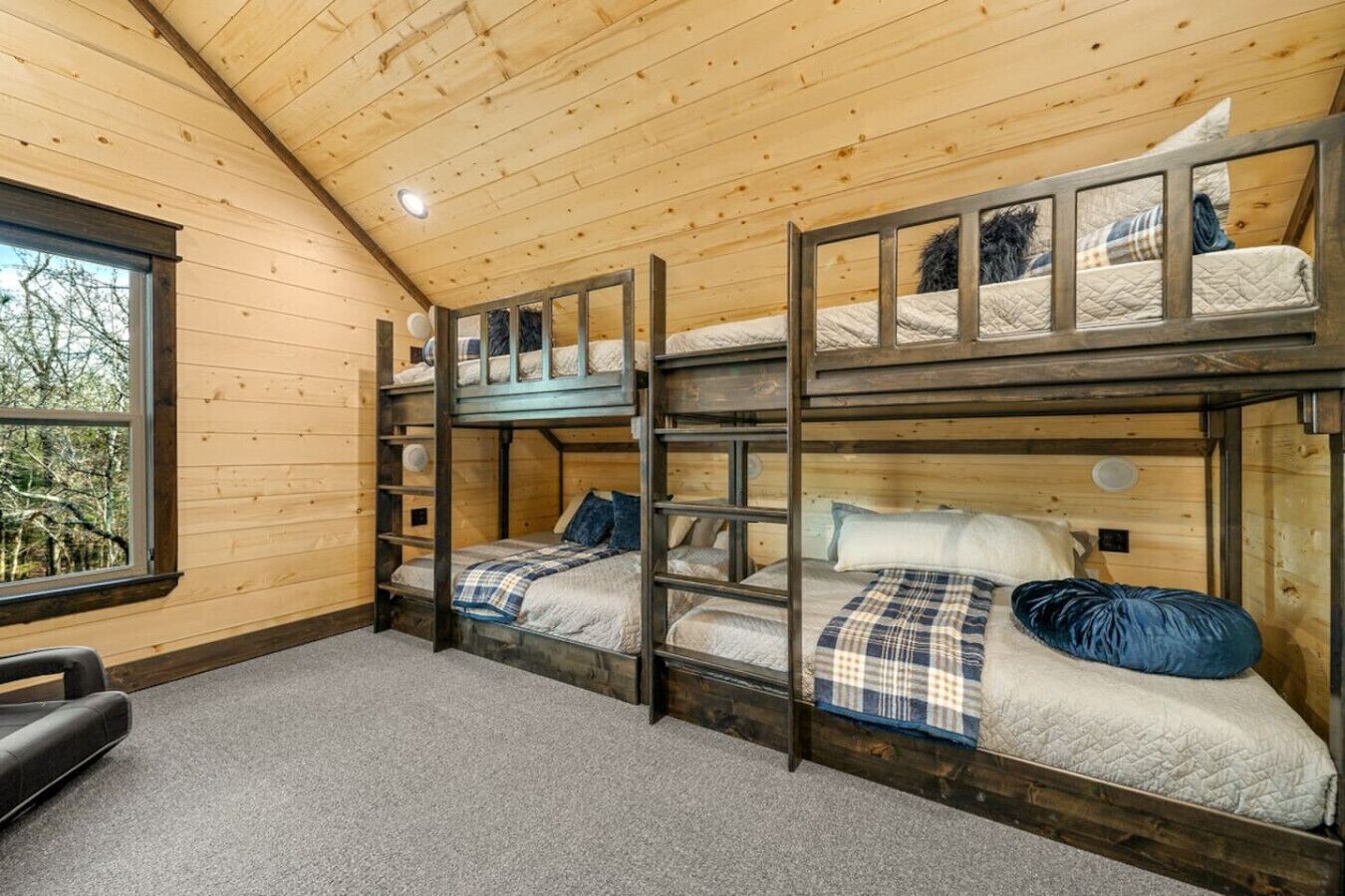 Une cabine équipée de trois lits superposés, d’une fenêtre donnant sur la forêt et d’un plancher recouvert de moquette.