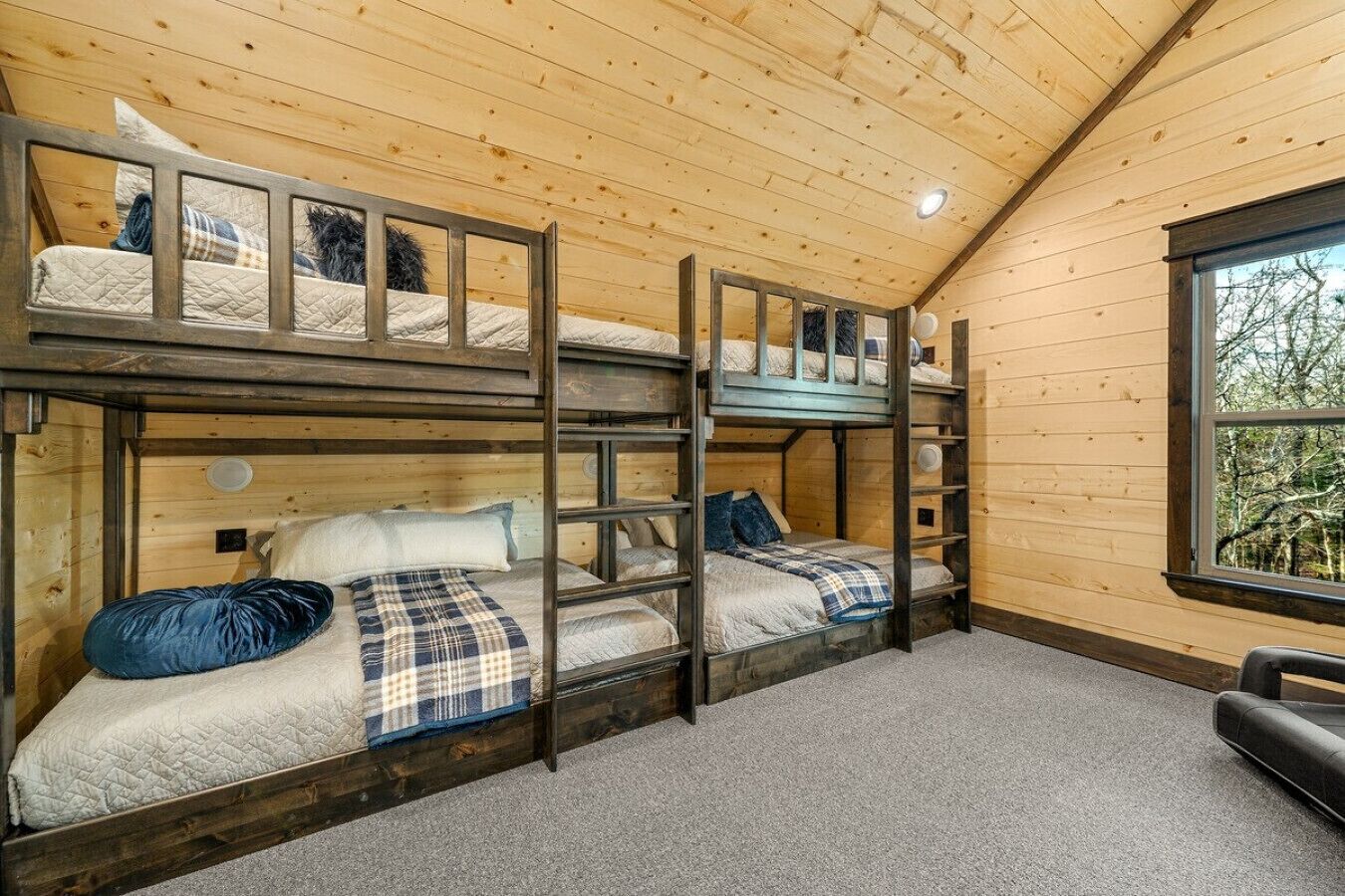 Een slaapkamer met stapelbed, houten wanden en een raam.