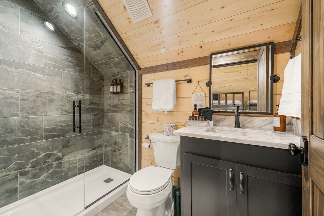 Une salle de bain moderne avec une douche à parois de verre, des toilettes et un meuble-lavabo avec un miroir.