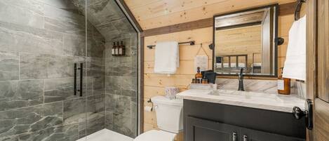 Une salle de bain moderne avec une douche à parois de verre, des toilettes et un meuble-lavabo avec un miroir.