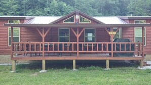 Eine Holzhütte mit Veranda, Hinweisschild und Grill.