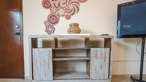 Un meuble de rangement rustique en bois, agrémenté d’un vase décoratif, d’un téléviseur et d’une porte.
