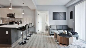 A modern kitchen with a central island, bar stools, and a dining area.