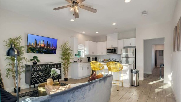 A modern living room with a sofa, a TV, and a cityscape painting.