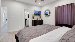 A bedroom with a bed, a ceiling fan, a TV, and a dresser.