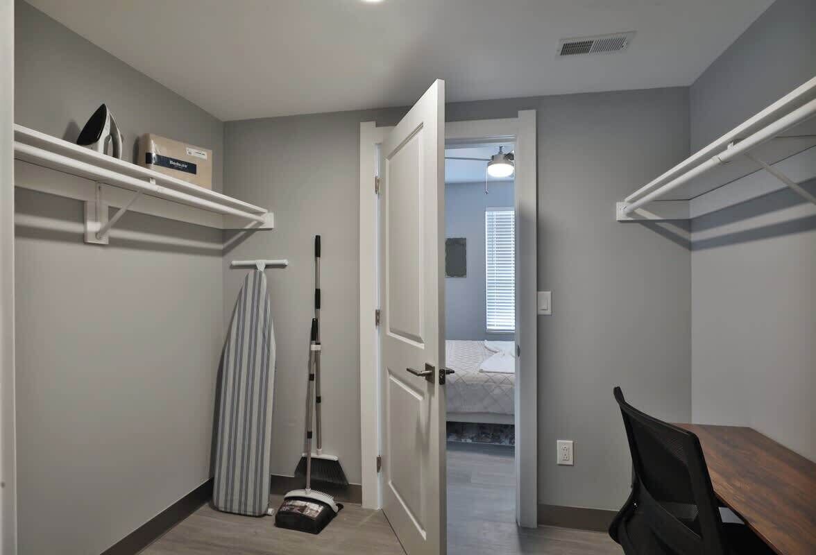 A compact room with a bed, a desk, and storage shelves.