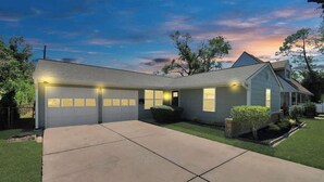 Une maison à deux étages avec un garage, une pelouse devant et une allée.