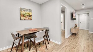 Un espace repas comprenant une table et des chaises en bois, un tapis et un panneau fixé au mur.