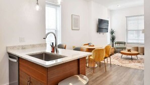 A modern kitchen with a central island, stainless steel sink, and overhead pendant lighting.