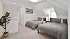 A modern bedroom with two beds, a large window, and a ceiling light. - Contemporary Vintage Home (Near Downtown!) (Columbus)