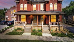 A two-story brick house with a front porch, two visible windows, and a garage. - Contemporary Vintage Home (Near Downtown!) (Columbus)