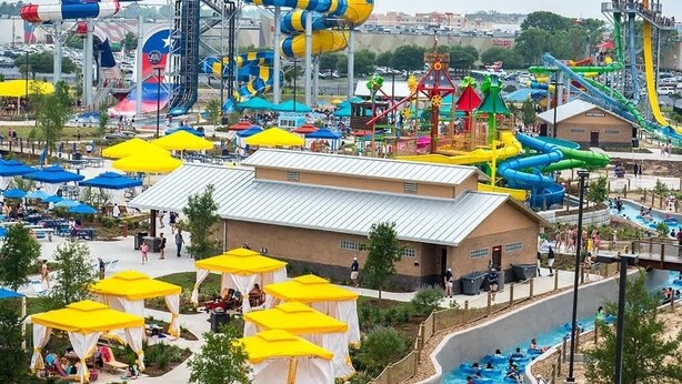 Un parc aquatique doté de nombreux toboggans et de plusieurs piscines, entouré d’espaces ombragés avec des parasols.