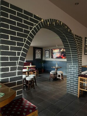 Un restaurant chaleureux avec une arche en briques, des tables et des chaises en bois.