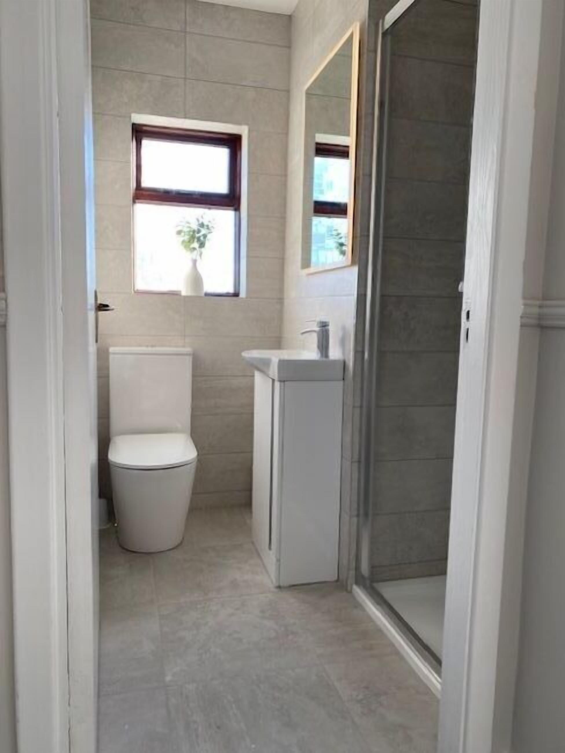 Een kleine badkamer met toilet, wastafel en een raam.
