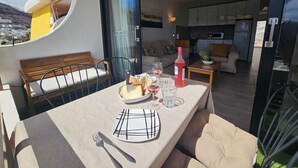 A dining area with a table set for two, a sofa, and a view of the kitchen and living room. - Modern Apartment With Sea View With Pool Puerto Rico (Mogan)