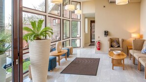 A spacious lobby with large windows, a reception desk, comfortable seating, and a fire extinguisher.