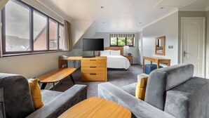 A modern bedroom with a large window, a desk, a bed, and a sofa.
