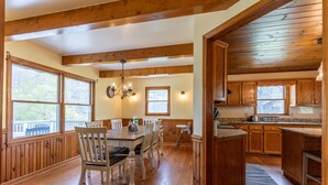 Una cocina amplia con armarios de madera, un comedor con mesa y sillas, y ventanas grandes que dejan entrar luz natural.