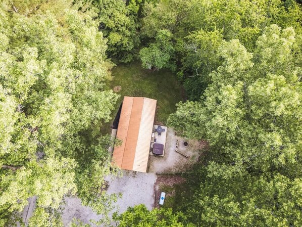 An aerial view of a house surrounded by dense green trees.