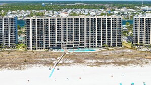 A high-rise hotel with multiple floors, a beach with umbrellas, and a clear view of the ocean.