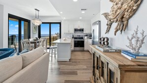 A modern kitchen with white cabinets, a central island, and a view to the outside.
