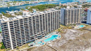A high-rise hotel with multiple floors, a swimming pool, and a marina in the background.
