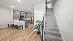 Une cuisine moderne dotée d’un îlot central, de tabourets de bar et d’un escalier menant à un autre niveau.