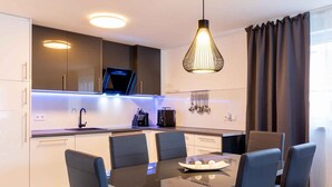 A modern kitchen with a dining area, including a table with chairs, a pendant light, and a TV above the counter. - Holiday home mit Pool und Meerblick (Vela Luka)