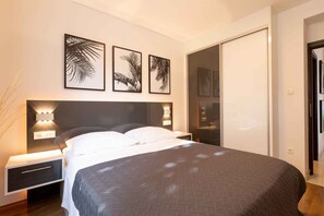 A bedroom with a bed, bedside tables, and wall-mounted light fixtures.