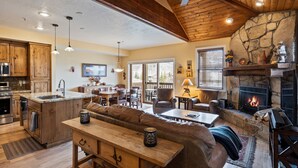 Un vaste espace de vie agrémenté d’une cheminée en pierre, d’un plafond en bois et d’un coin salon confortable.