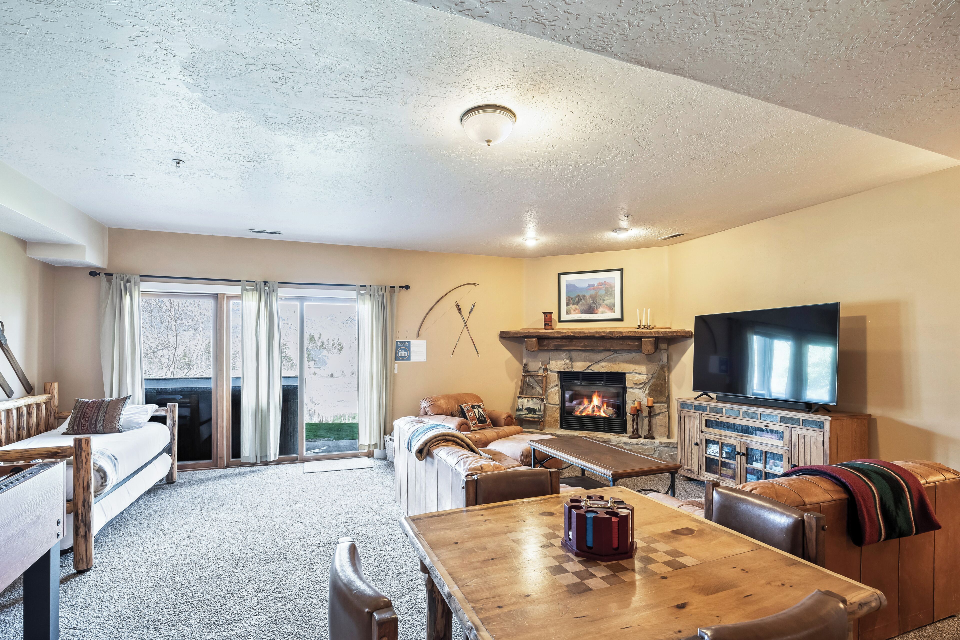 A cozy living room with a fireplace, a television, and a dining area with a chessboard.
