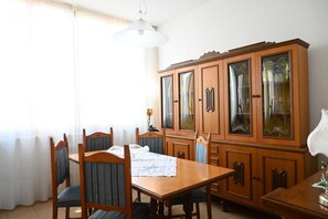 A dining area with a wooden table, chairs, and a cabinet with glass doors.