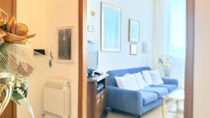 Un salón con un sofá azul, una mesa de centro y cuadros enmarcados en la pared.
