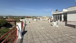Terraza en la azotea con suelo de baldosas, barandillas y vistas de edificios circundantes.