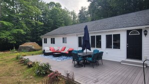 Una terraza con mobiliario exterior, una piedra y una casa con puerta negra.