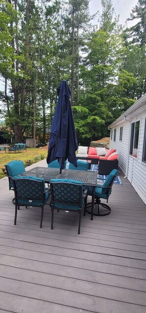 Una terraza con una mesa y sillas, un paraguas cubierto y un sofá con cojines.