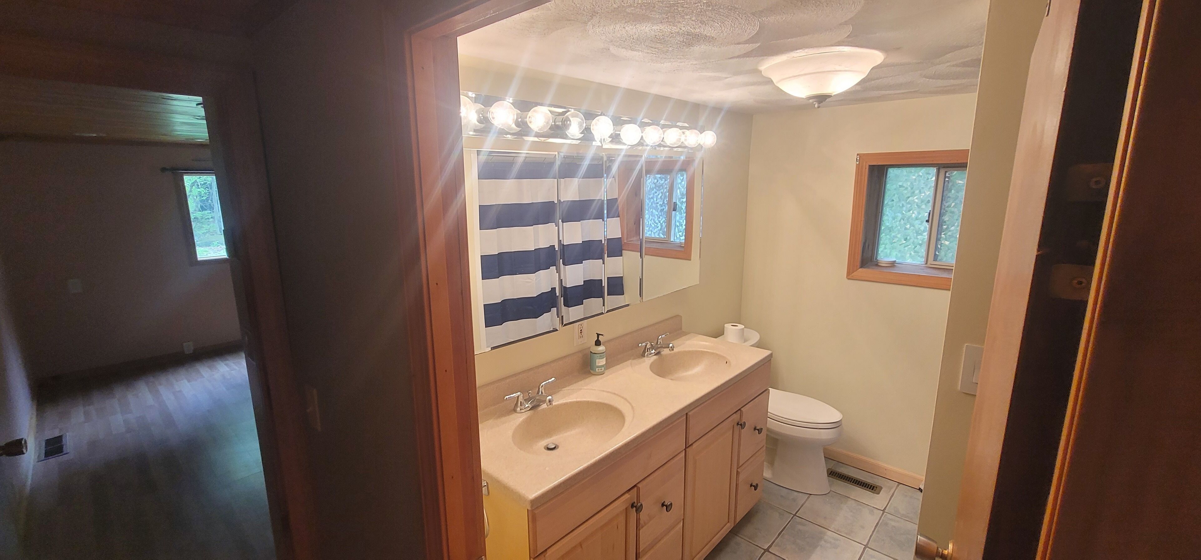 Ein Badezimmer mit zwei Waschbecken, einer Toilette und einem Spiegel mit Beleuchtung.