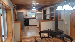 Una cocina con armarios de madera, un refrigerador y una zona de comedor con una mesa y sillas.