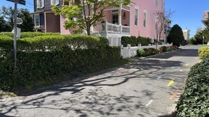 Eine Wohnstraße mit einem rosafarbenen Haus, einem weißen Zaun und einem Baum.