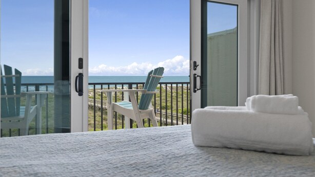 Een balkon met een stoel en een handdoek, met uitzicht op de kust.