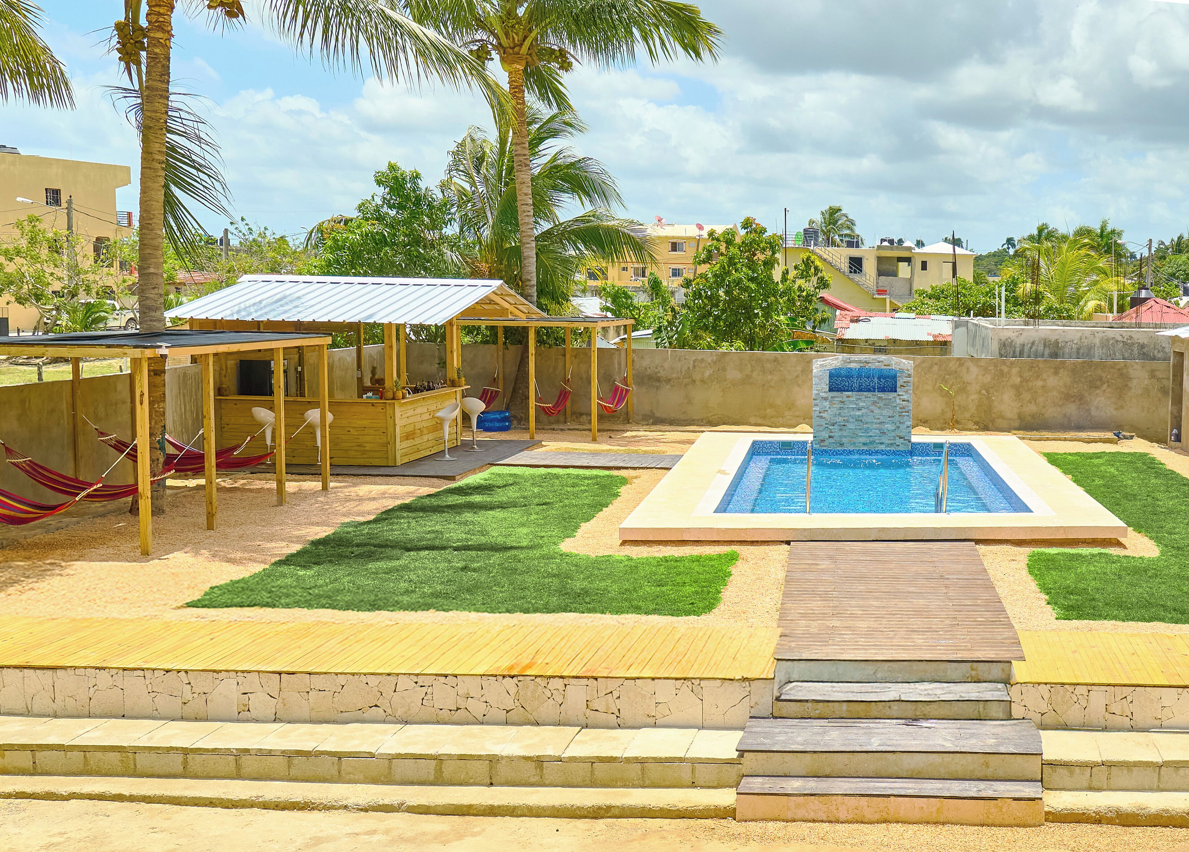 A pool area with a wooden deck, a small bar, and a hammock.