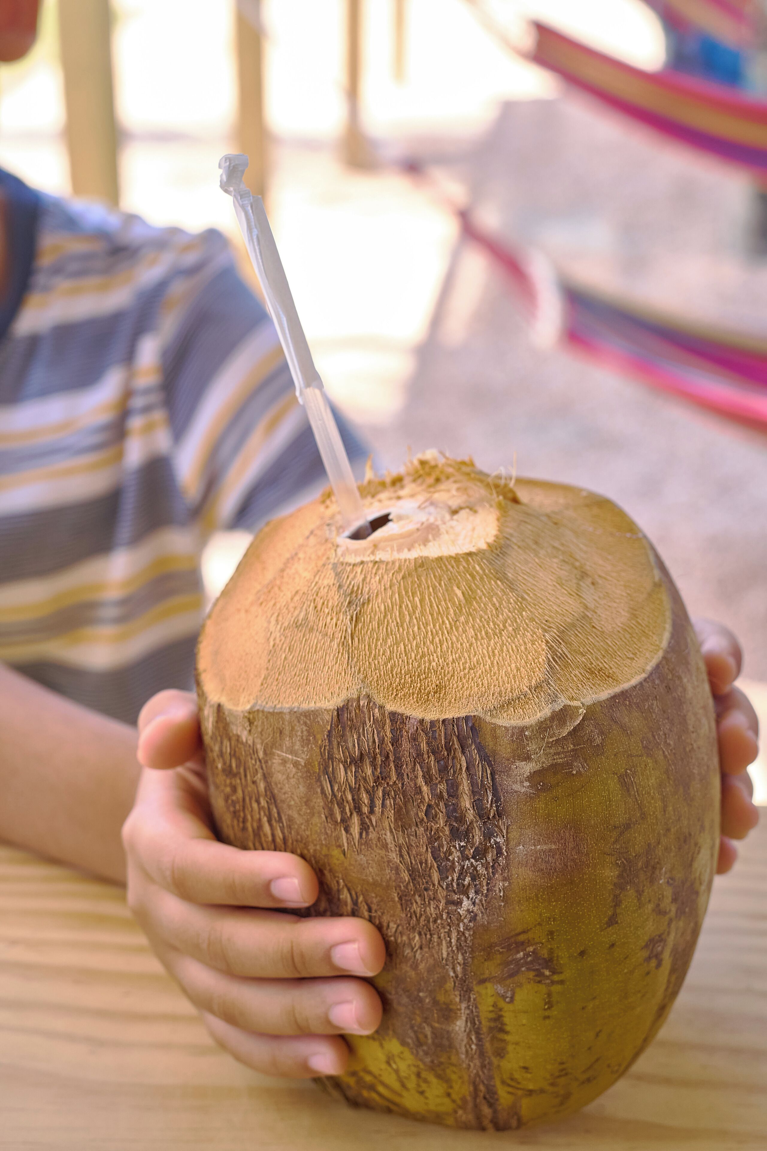 Une personne tenant une noix de coco dans laquelle est insérée une paille.