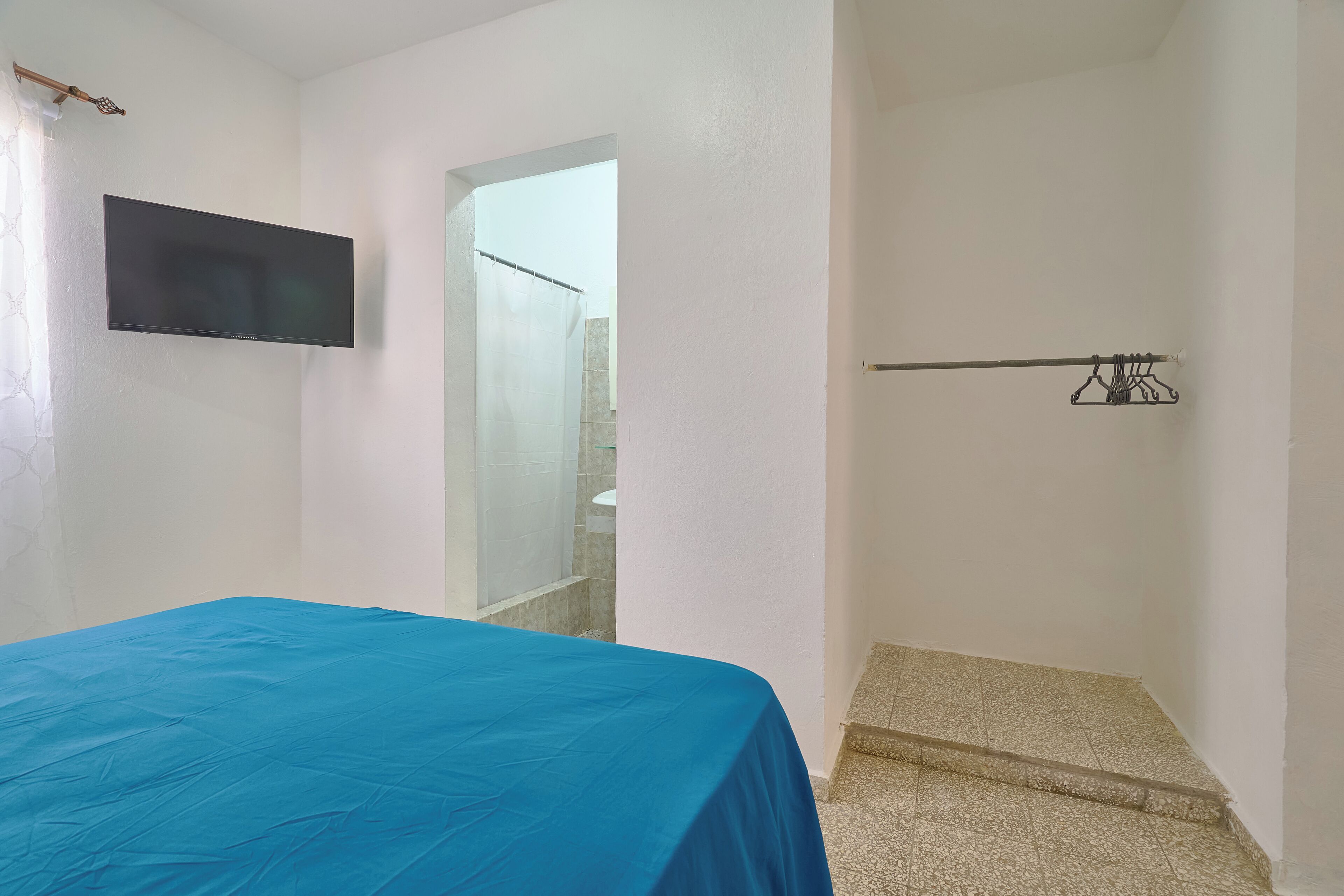 Una habitación con cama, televisor montado, zona de ducha y una pequeña escalera.