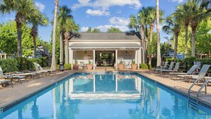 A swimming pool with lounge chairs, palm trees, and a covered pavilion.