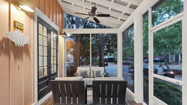 A covered porch with two chairs, a ceiling fan, and a view of the street.