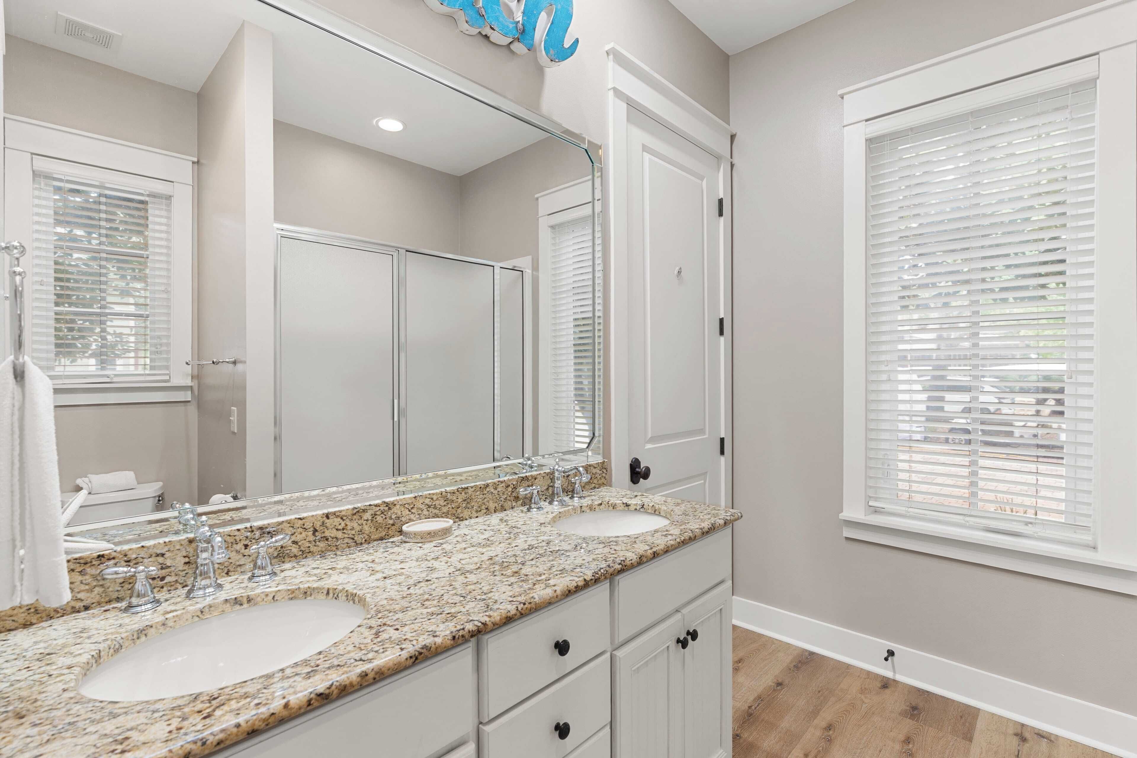 Un baño con dos lavamanos, un espejo grande y muebles blancos.