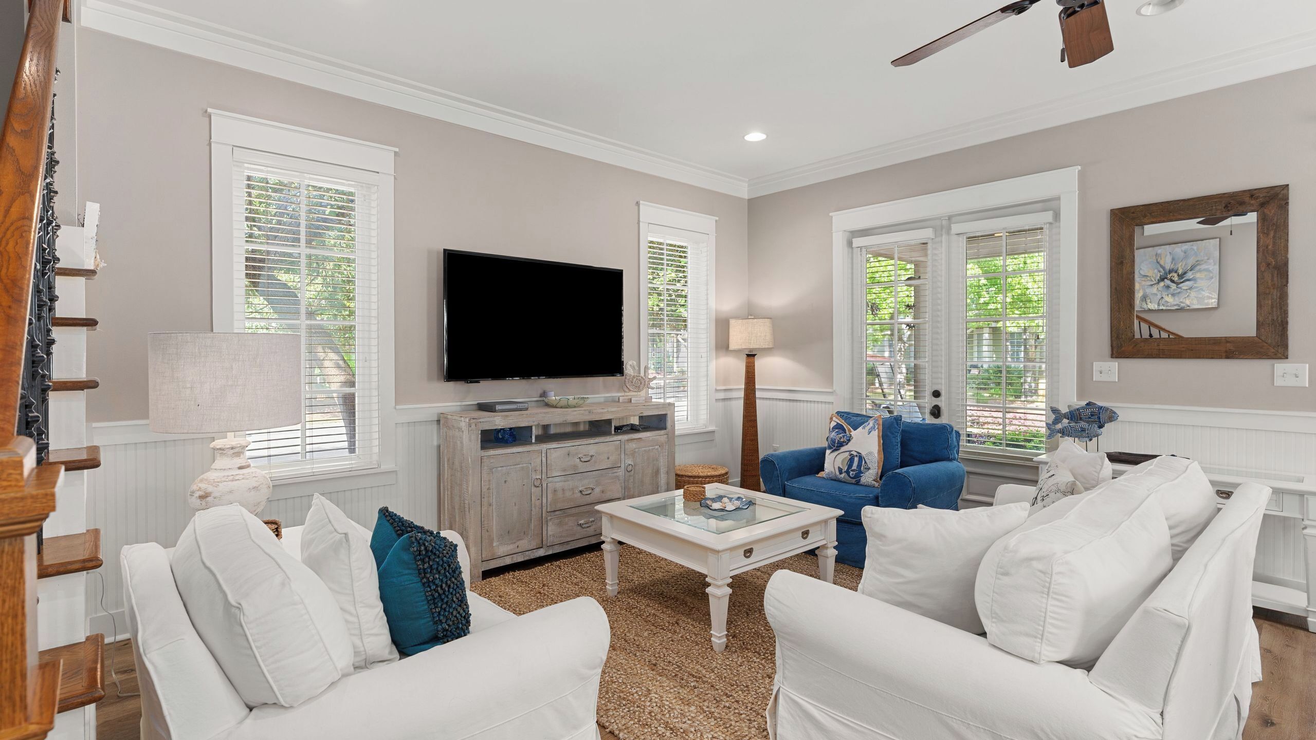 A living room with a TV, white sofas, a coffee table, and a blue sofa.