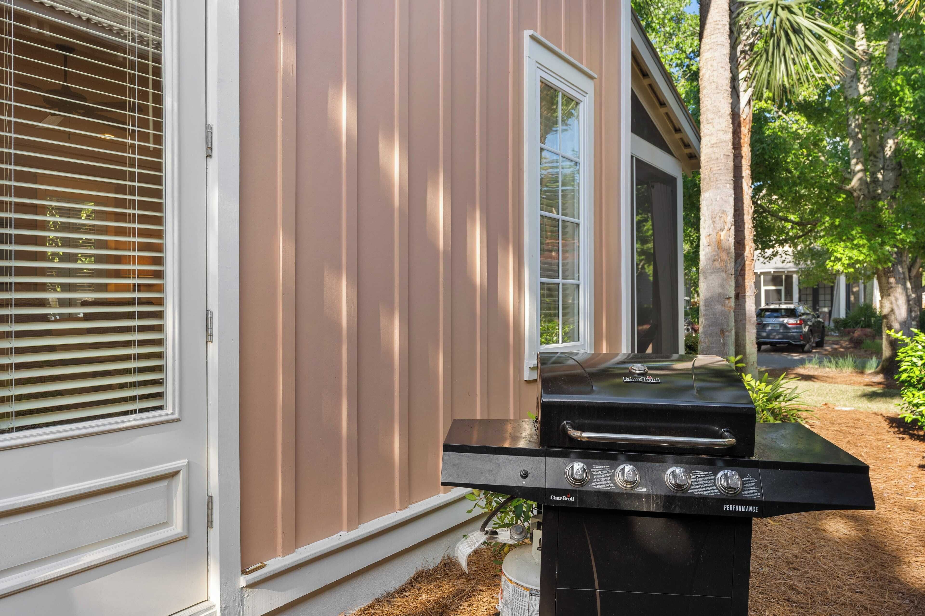 Un barbecue est installé à l’extérieur d’une maison qui possède une fenêtre et une porte.