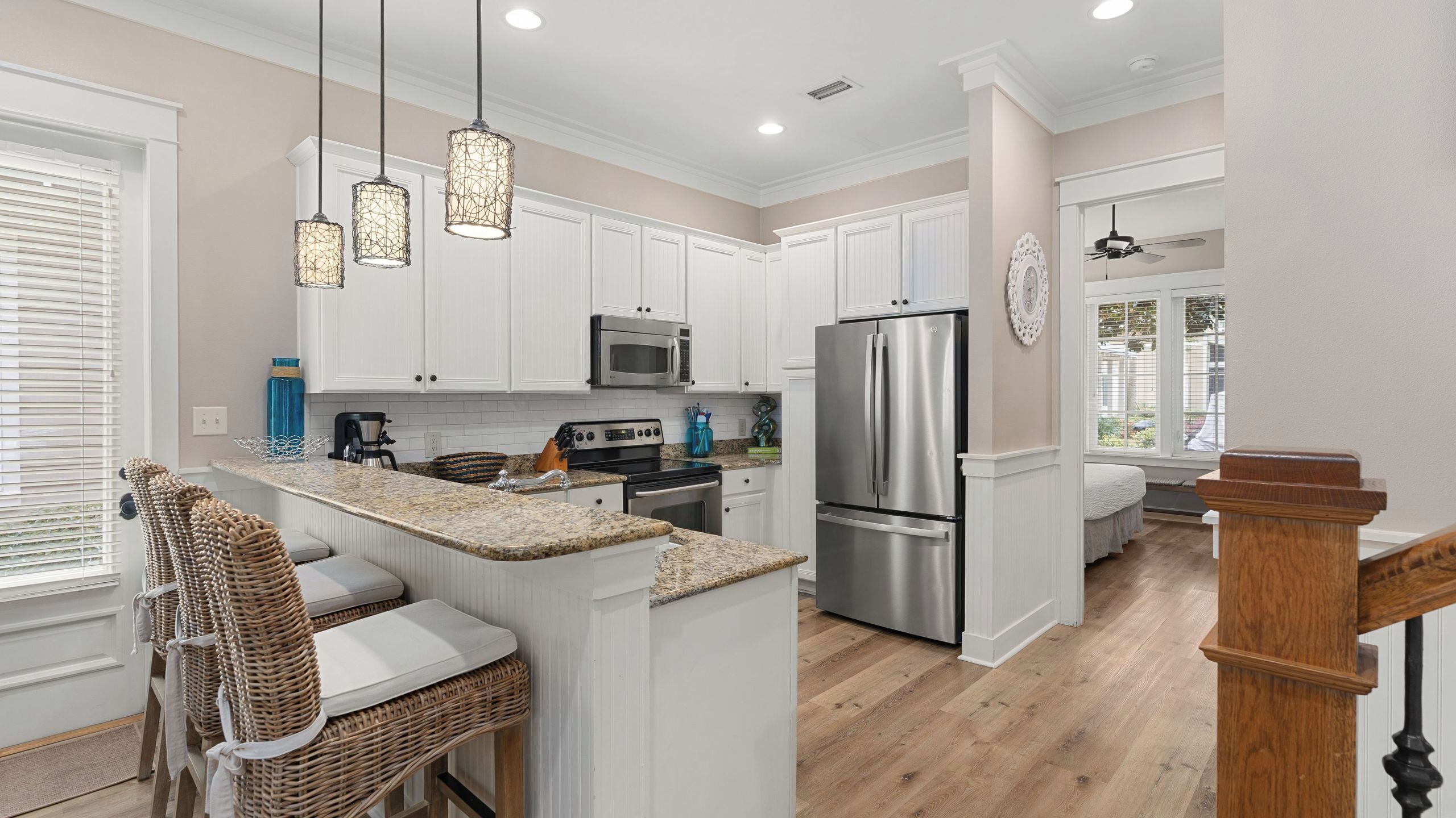 A kitchen with white cabinets, a stainless steel refrigerator, a microwave, and a coffee maker.