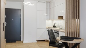 Una cocina moderna con armarios blancos, una silla negra y una mesa redonda de madera.